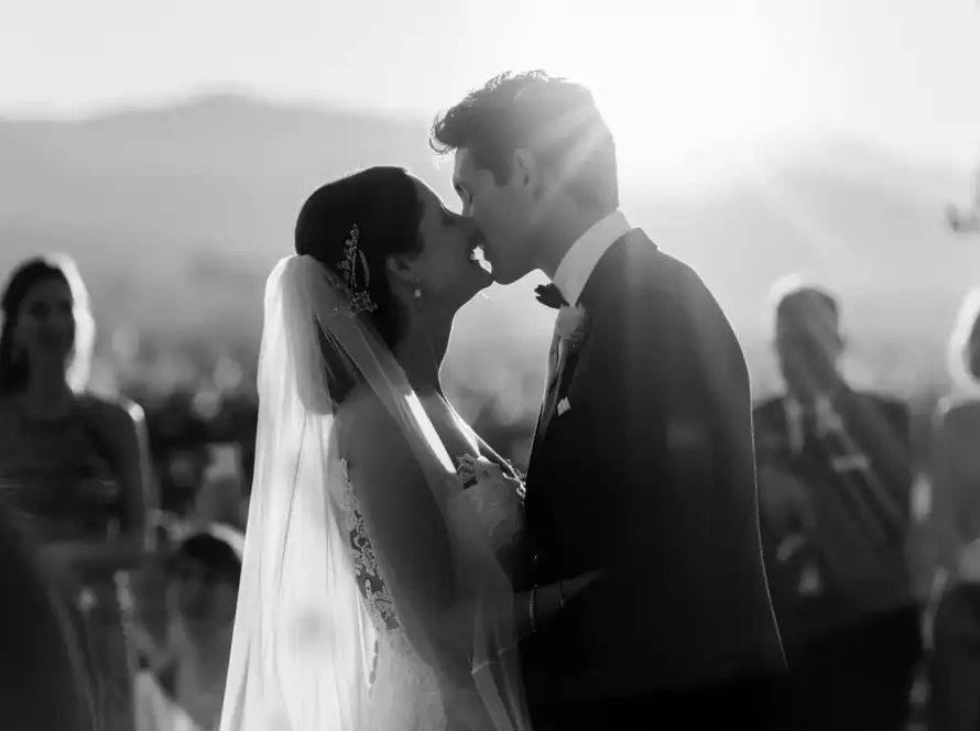 Black and white photo of couple's first kiss at Hunter Valley vineyard wedding ceremony with mountain backdrop